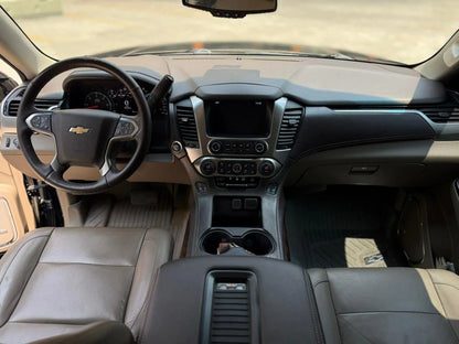 SUV Chevrolet Tahoe LT 2017 de color gris oscuro conducido en la calle, vista lateral con detalles del vehículo.