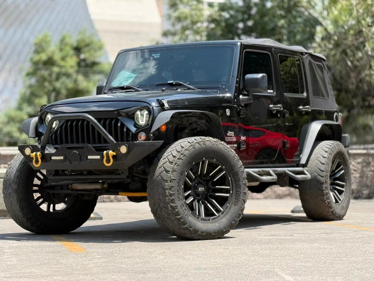Vehículo Jeep Wrangler Unlimited Sport 2017 offroad en color negro, mostrado desde un ángulo lateral.