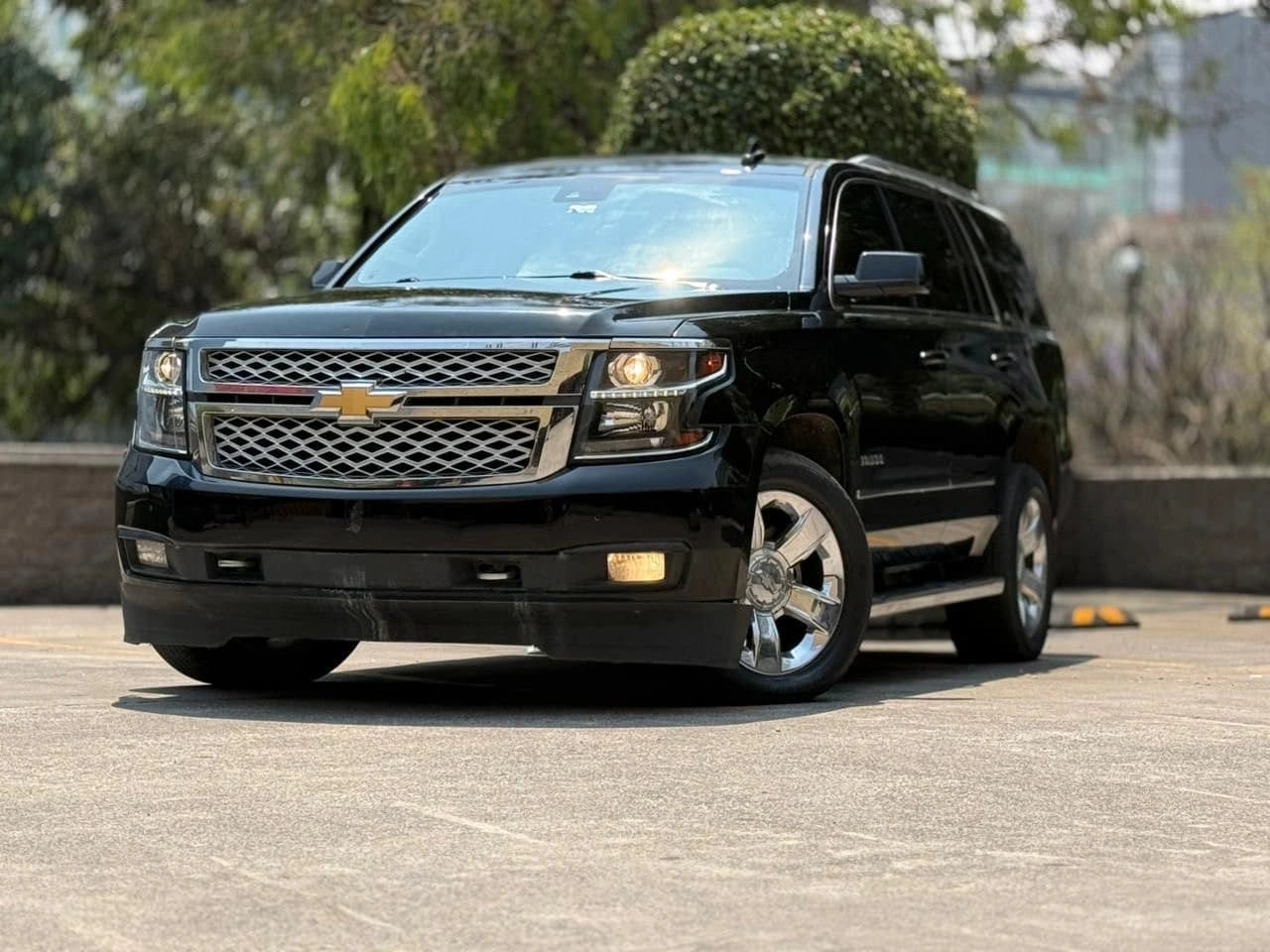 SUV Chevrolet Tahoe LT 2017 de color gris oscuro, vista lateral del vehículo en un entorno urbano.